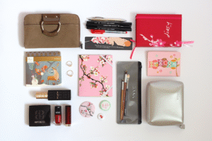 What's in my bag: Inhalt einer Damentasche ausgebreitet auf weißem Hintergrund