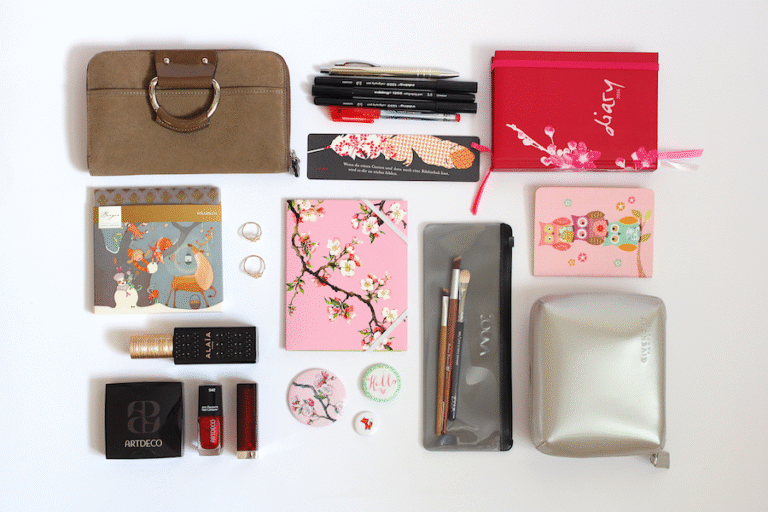 What's in my bag: Inhalt einer Damentasche ausgebreitet auf weißem Hintergrund