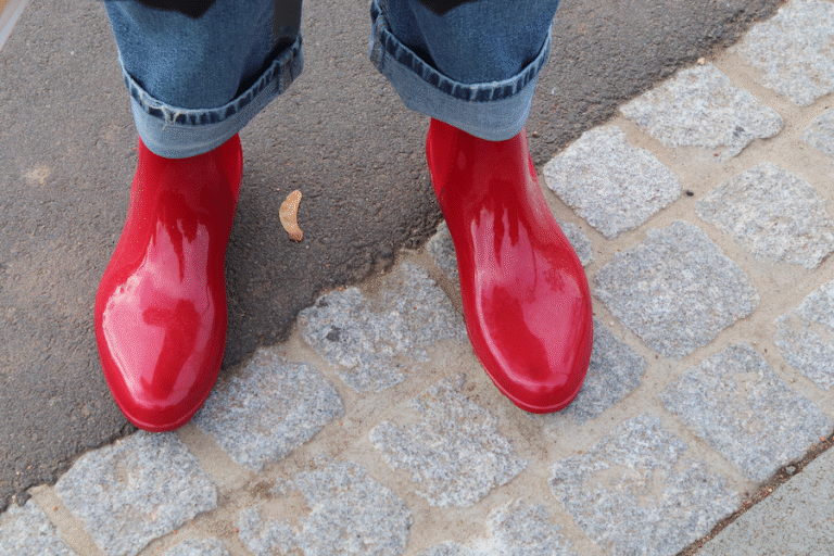 Blick nach unten: eine Dame hat rote Regenstiefel an